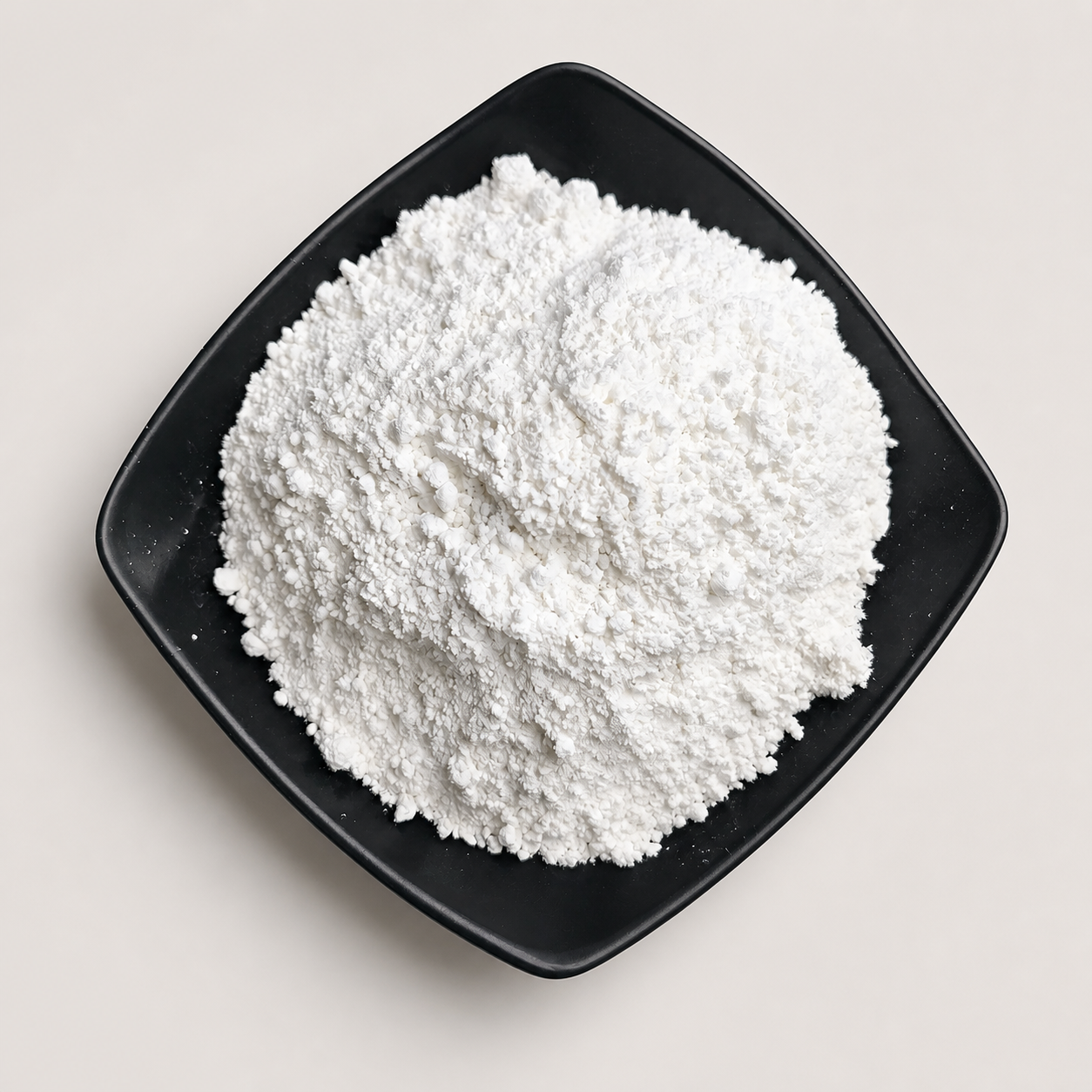 White calcium carbonate powder in a black sample dish